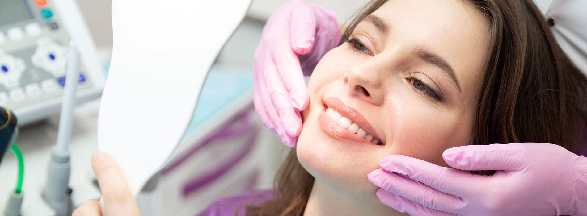 A person receiving dental care, with a dentist or hygienist performing the procedure and a medical device present.