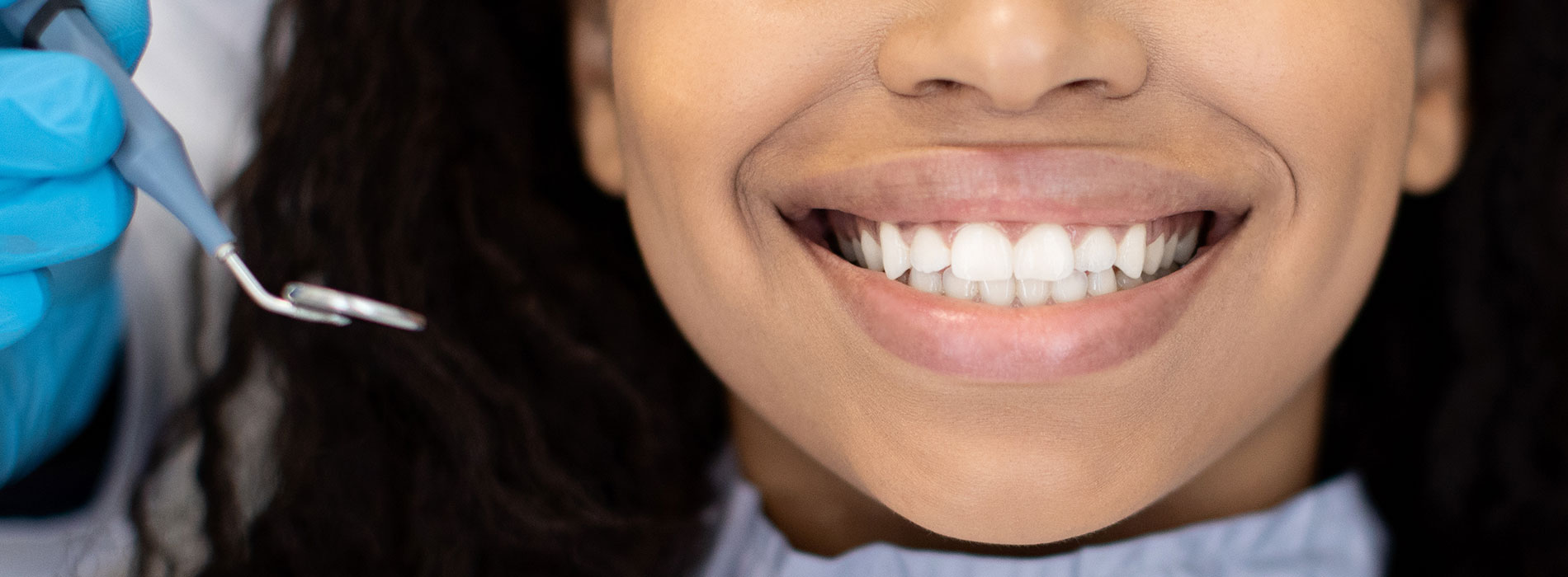 A smiling woman in a dental chair receiving dental treatment.