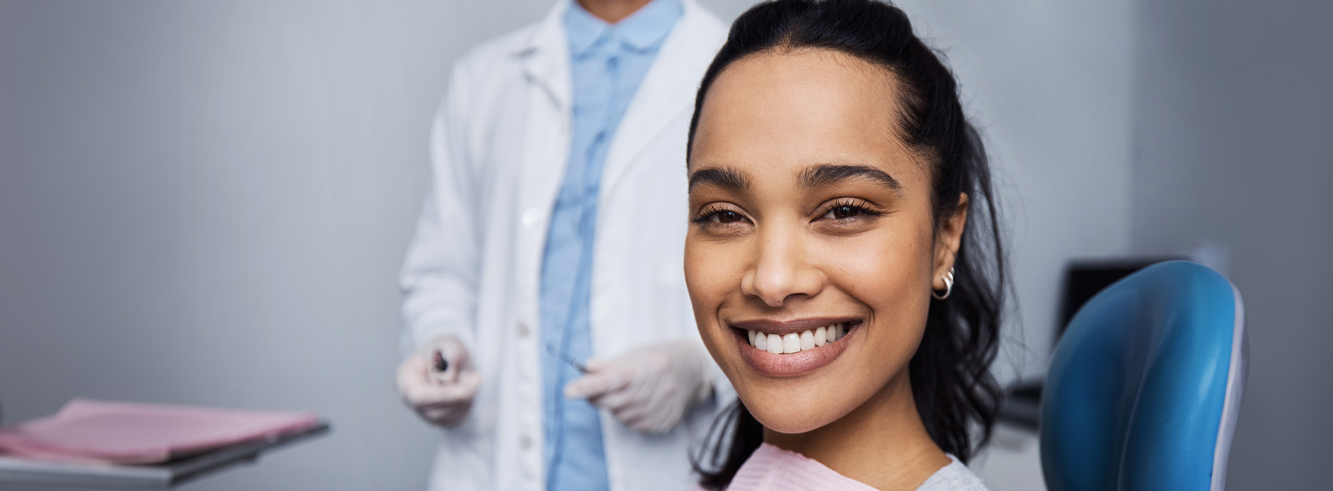 Woman in a dental office, smiling at the camera.