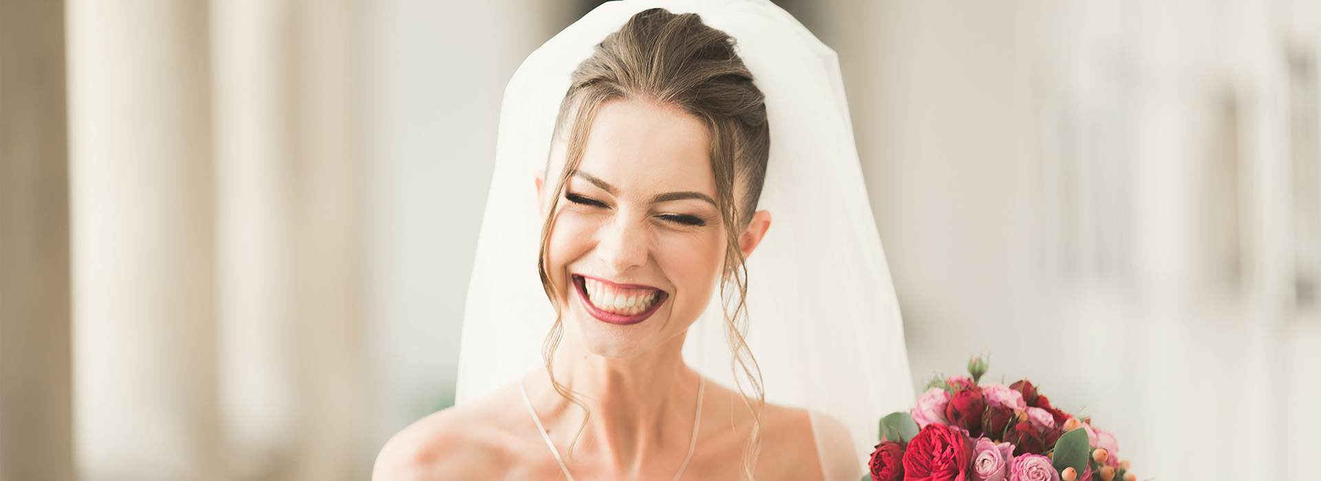 The image shows a bride, presumably at her wedding ceremony or reception, with a joyful expression and a bouquet of flowers.