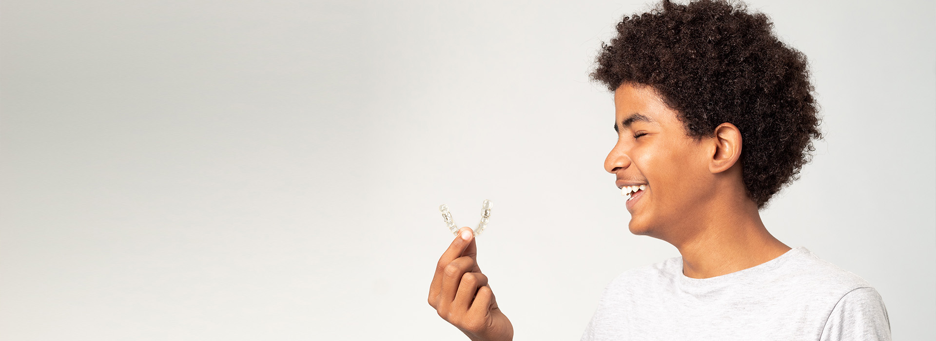 A young person holds a white flower, smiling at the camera.