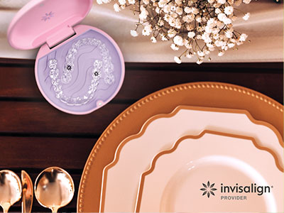 The image displays a collection of tableware, including plates, bowls, and serving dishes, arranged on a wooden surface with a pink box containing what appears to be a dental implant in the background.