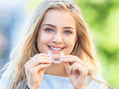 A smiling woman holding a toothbrush, showcasing dental care product.