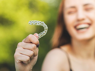 A smiling woman holding a toothbrush with bristles.