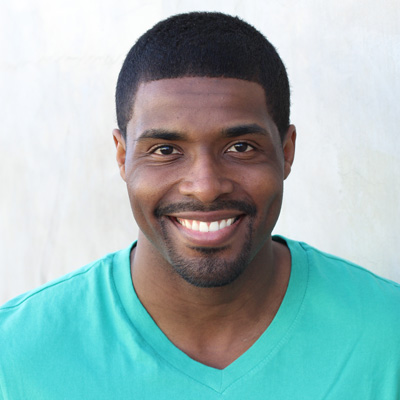 An elderly couple smiling and embracing, with the man wearing a white beard and mustache, both dressed casually in outdoor attire, posing for a portrait.