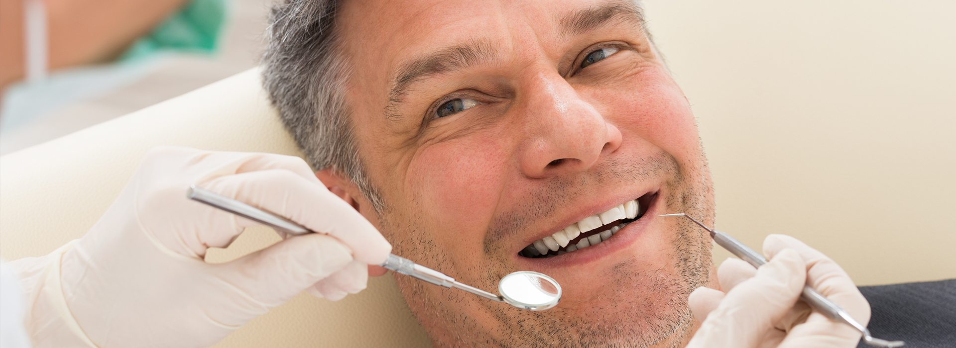 Man sitting in dental chair, smiling while receiving dental care.