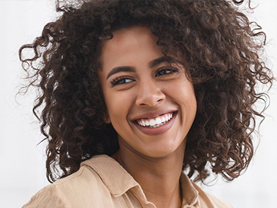 A woman with curly hair, smiling at the camera.