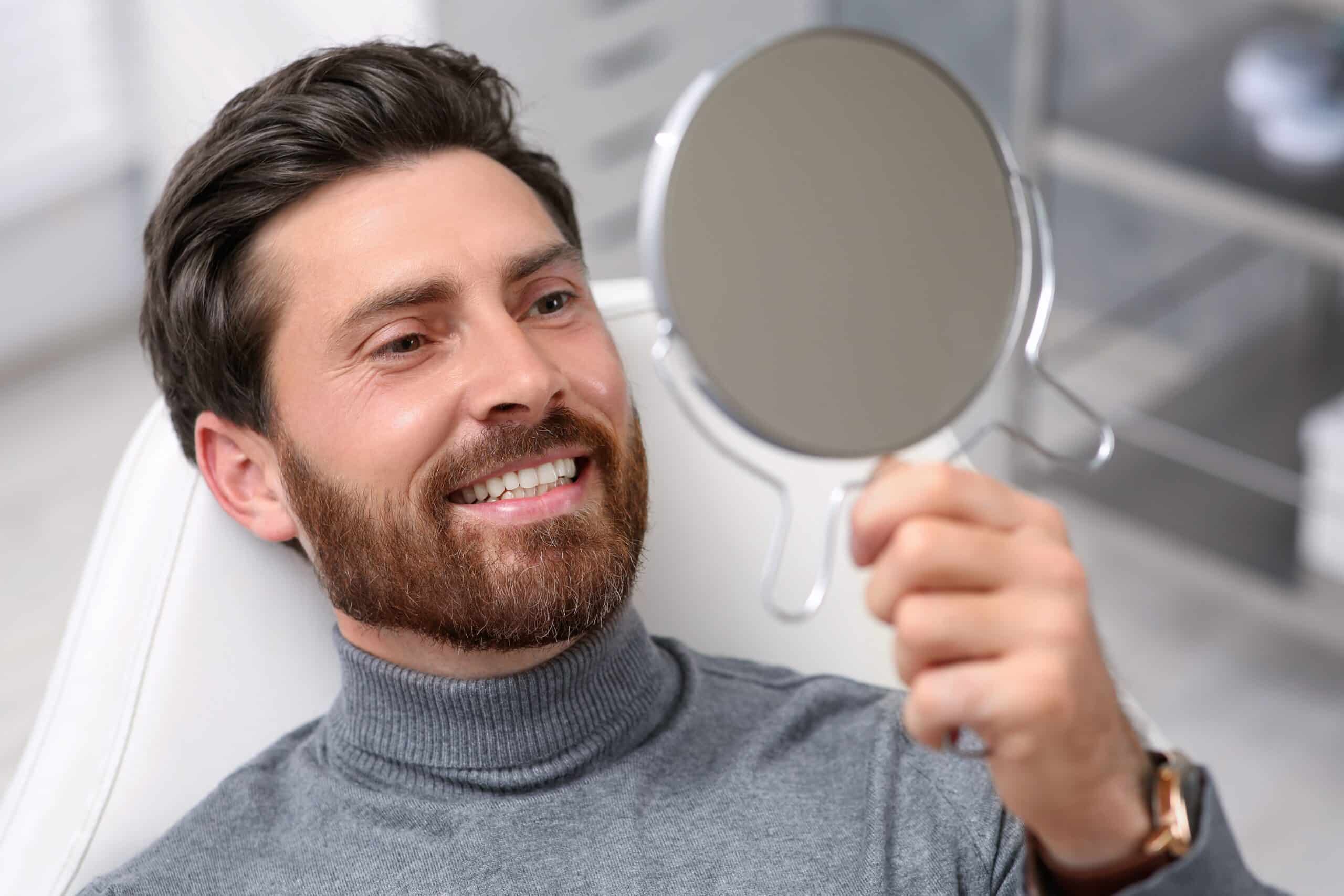 Man,Looking,At,His,New,Dental,Implants,In,Mirror,Indoors