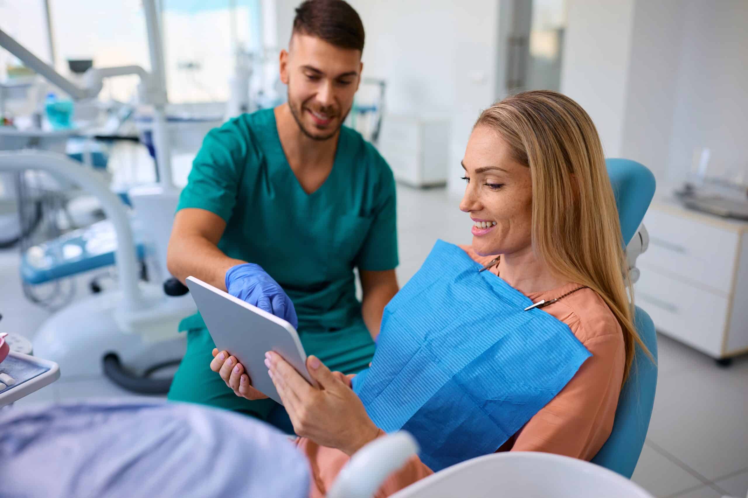 Happy,Dentist,And,His,Female,Patient,Using,Touchpad,During,Teeth
